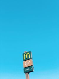 Low angle view of road sign against blue sky