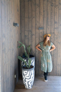 Woman with potted plants against wooden wall