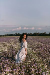 Young woman standing on field against sky