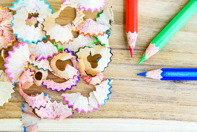 Directly above view of colorful pencils and shavings on wooden table