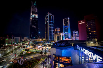Illuminated modern buildings in city against sky at night