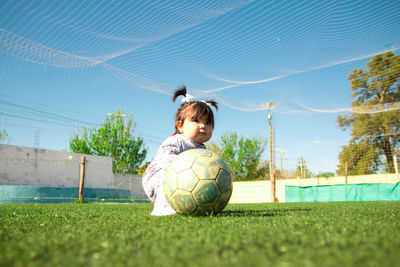 Girl with ball on soccer field against blue sky