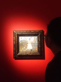 Portrait of woman photographing through red wall