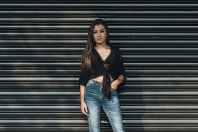 Portrait of young woman standing against shutter