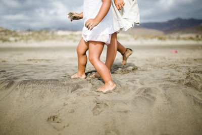 Low section of girls walking on sandy beach