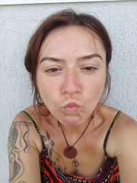 Close-up portrait of young woman against wall
