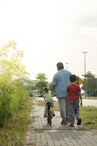 Rear view of people walking on road against sky