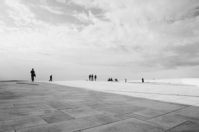 People at oslo opera house against cloudy sky