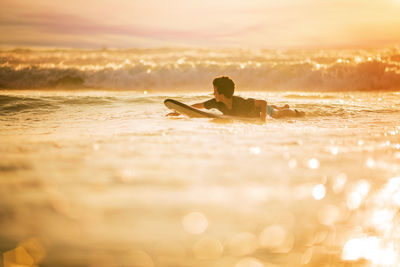 Surfing at sunset. outdoor active lifestyle. young boy riding wave at sunset
