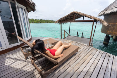 Woman relaxing in swimming pool against sea