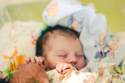 Close-up of cute baby lying on bed at home and holding hands with daddy