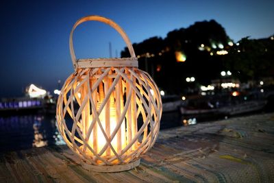 Close-up of illuminated lighting equipment on table against sky at night