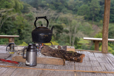 Close-up of tea kettle on stove against trees