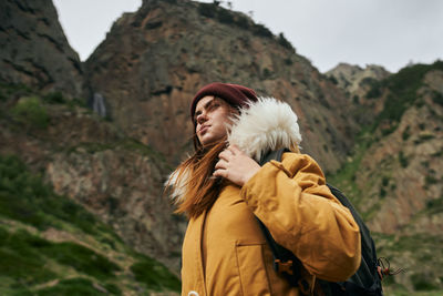 Portrait of young woman standing against mountain