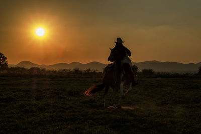 View of horse riding on field during sunset