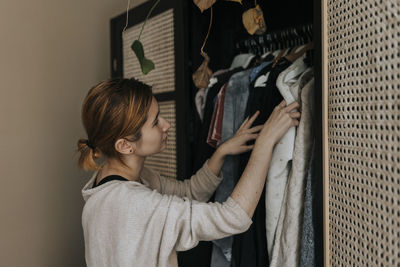 Non-binary person choosing clothes from wardrobe at home