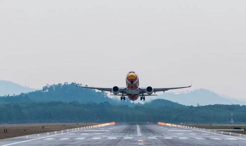 Airplane taking off on runway against sky