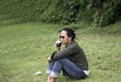 Full length of man photographing while sitting on land