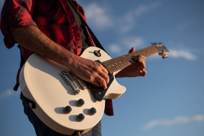 Low angle view of man playing guitar against sky