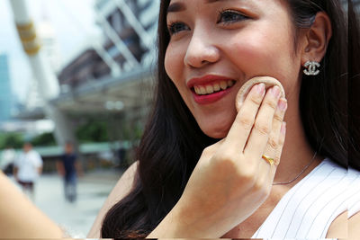 Woman applying powder in city