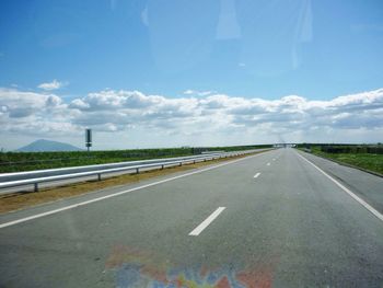 Empty country road against cloudy sky