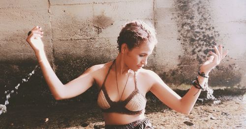 Young woman splashing water against wall