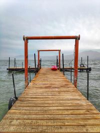 Wooden pier on sea against sky