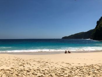 Scenic view of beach against clear blue sky