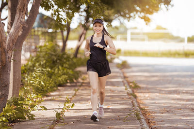 Full length portrait of woman standing on footpath