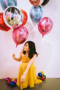 Full length of happy girl with colorful balloons