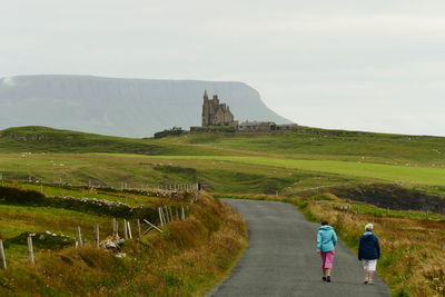 Rear view of people walking along country road