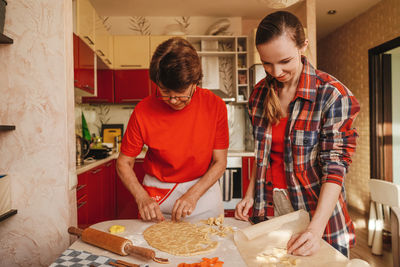 Cheerful mother and daughter making cookies at home