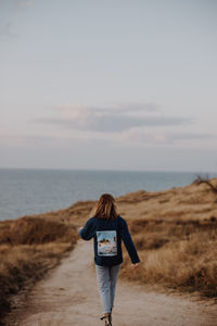 Rear view of man standing on beach against sky
