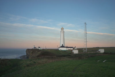 Lighthouse by sea against sky