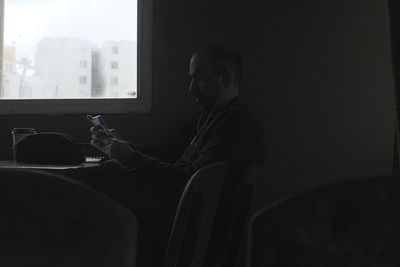 Side view of young man sitting on chair