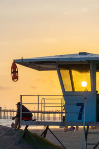 Airplane on beach against sky during sunset