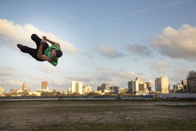 Man performing stunt over field against sky