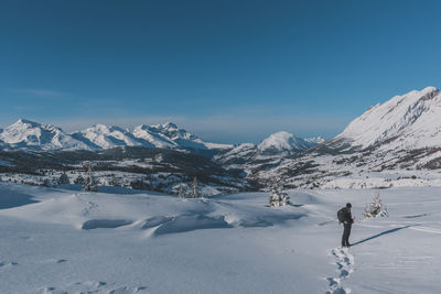 An unrecognizable male hiker wearing snowshoes walking in the french alps