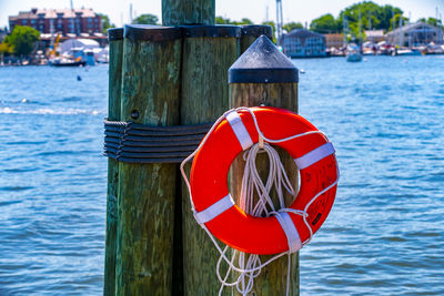 Close-up of red flags hanging on wooden post in sea