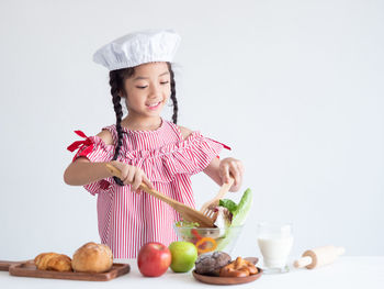 Girl preparing salad against white background