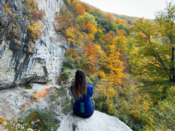 Rear view of woman sitting on rock
