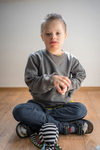 Portrait of cute boy sitting on hardwood floor