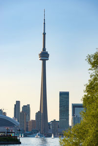 Cn tower by river against clear sky in city