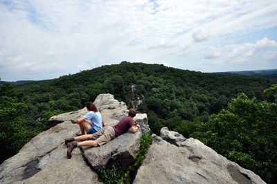 People on rock looking at mountain 