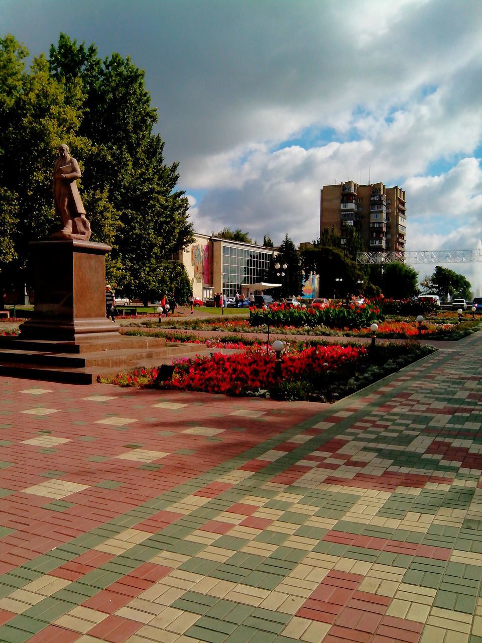 building exterior, architecture, sky, built structure, tree, cloud - sky, street, cloudy, city, growth, outdoors, cobblestone, cloud, plant, house, incidental people, road, day, no people, paving stone