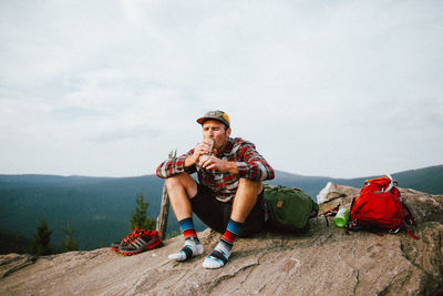 Friends sitting on mountain against sky