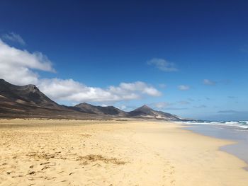 Scenic view of beach against blue sky