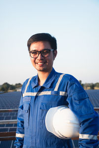 Portrait of young man standing against blue sky