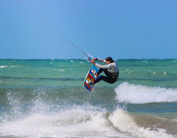 Man with umbrella on sea against clear sky