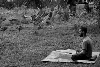 Side view of man sitting on field